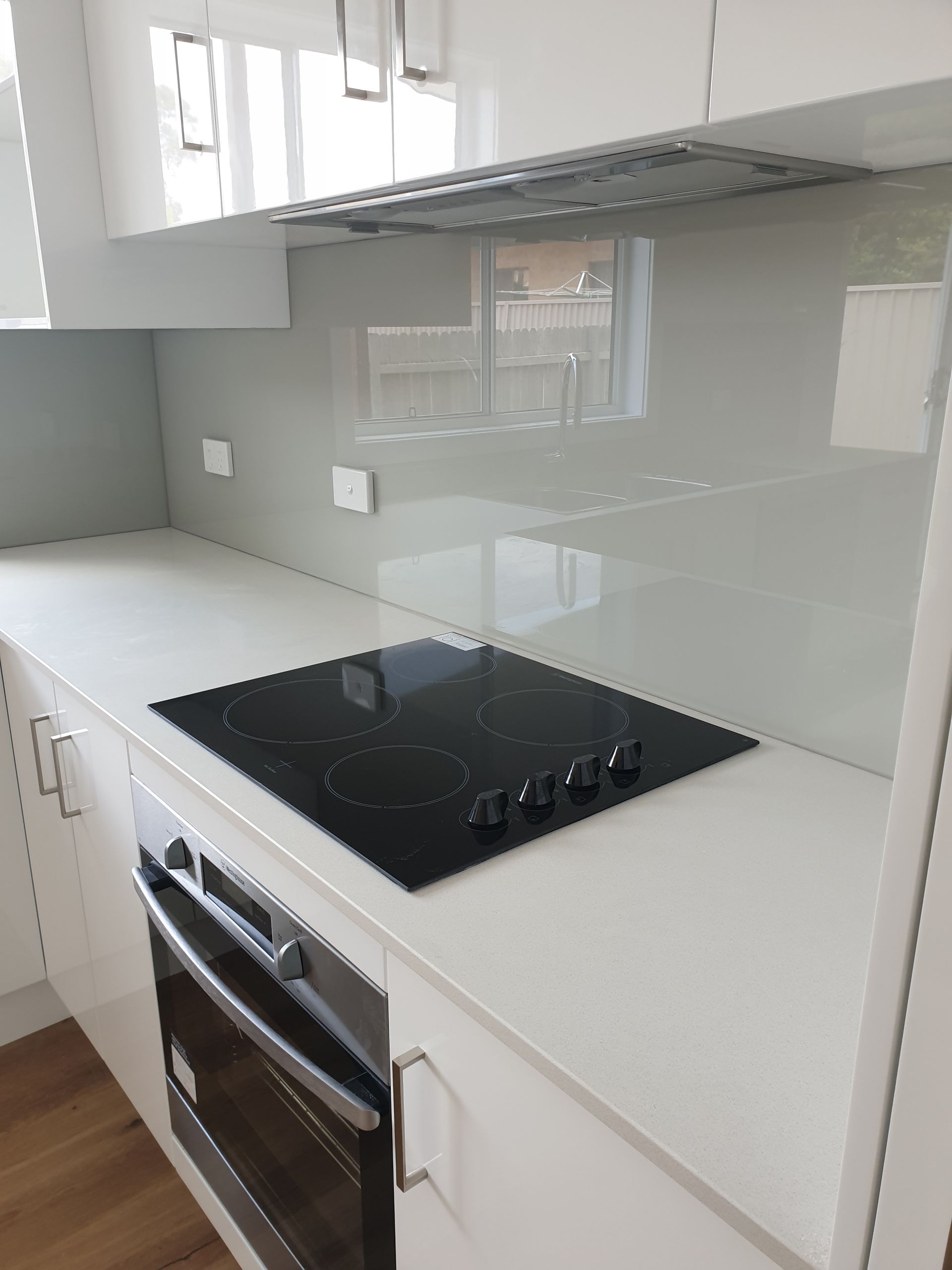 Modern Kitchen With White Cabinets Light Grey Backsplash — Local Glassmaster in Vincentia, NSW