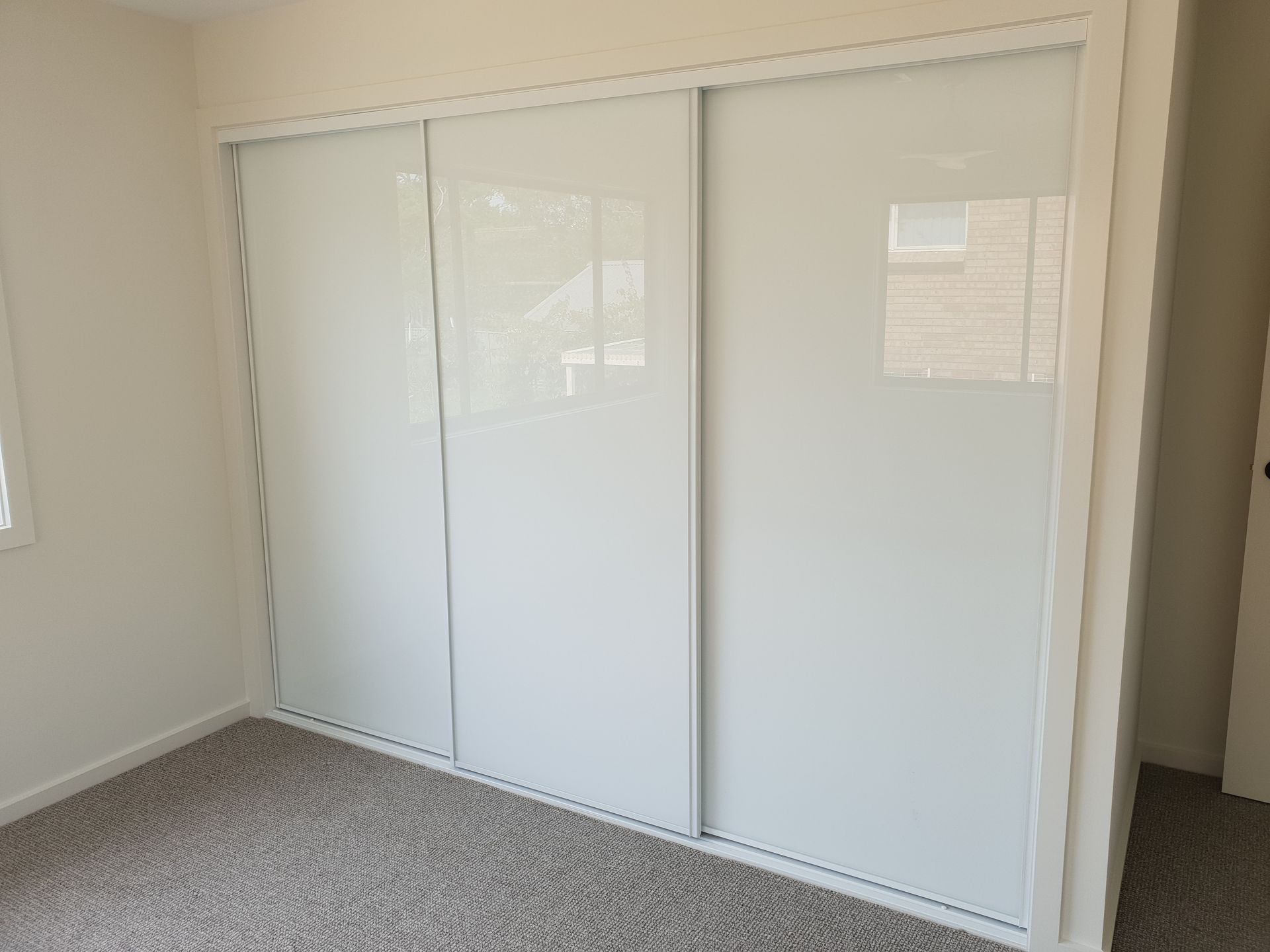 White Sliding Closet Doors in a Room With Grey Carpet — Local Glassmaster in Sanctuary Point, NSW