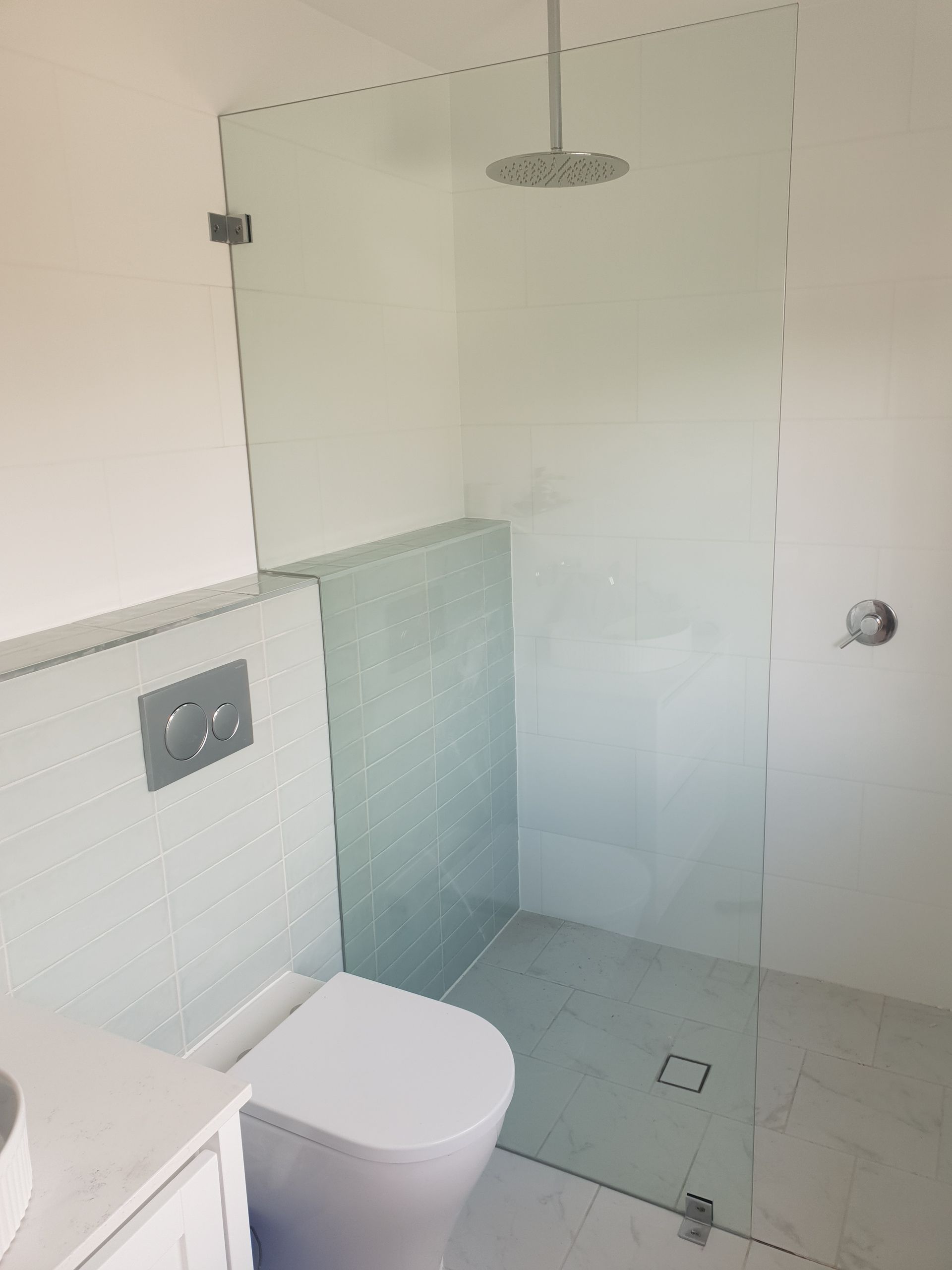 Glass-enclosed Shower With a Toilet in a White-tiled Bathroom — Local Glassmaster in Vincentia, NSW