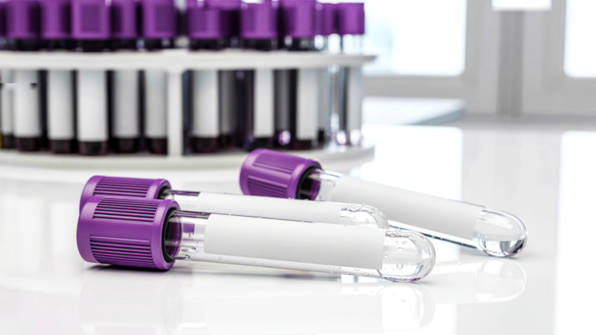 Hand in a blue glove holding two blood-filled vials against a tan background.