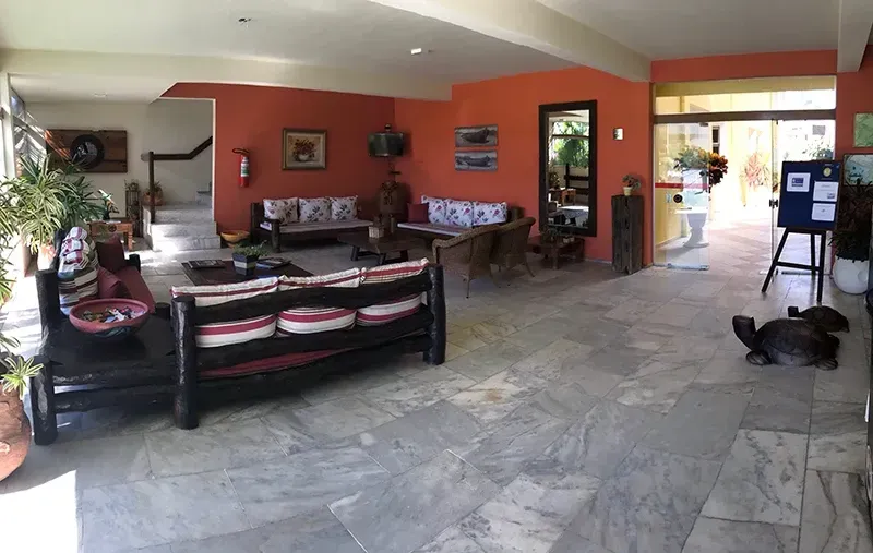 Hall de entrada com móveis de madeira, paredes de terracota e piso de azulejos. Um coelho está sentado perto da entrada.