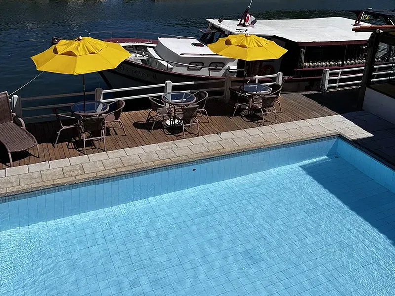 Piscina com guarda-sóis amarelos e cais para barcos.