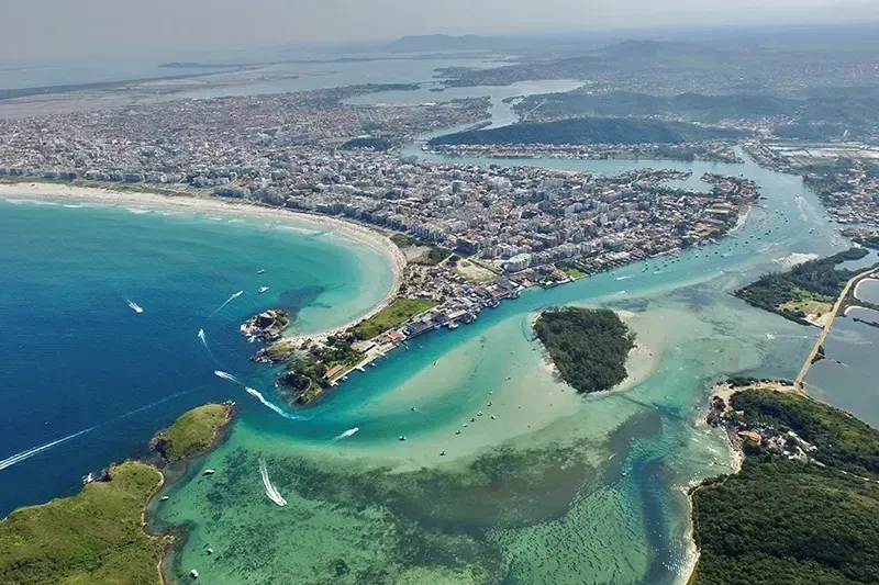 Cidade costeira com água turquesa, praia de areia e um canal que leva ao interior.