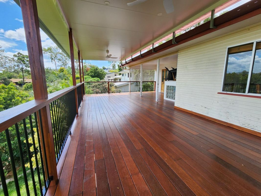Wooden deck with dark railing and a view of trees and homes.