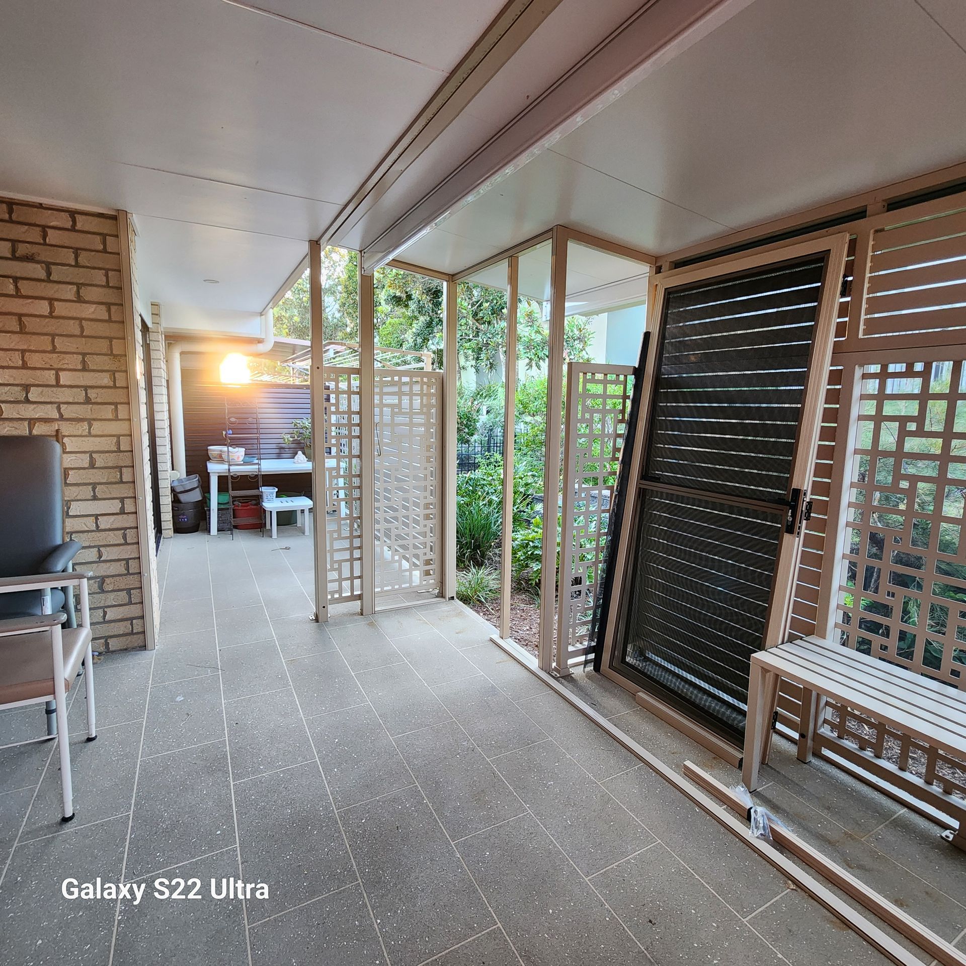 Covered patio with brick wall and trellis screens, looking towards a table setting.