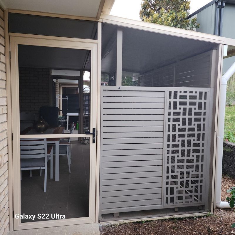 Outdoor enclosure with screened door and decorative gray panel.