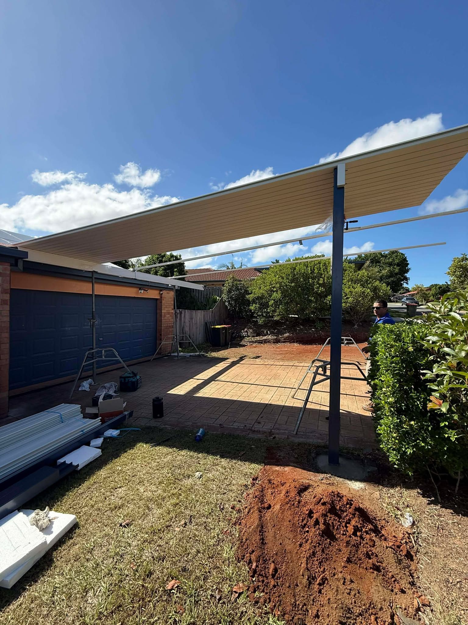 Metal deck frame under construction outdoors, surrounded by foliage and existing deck.