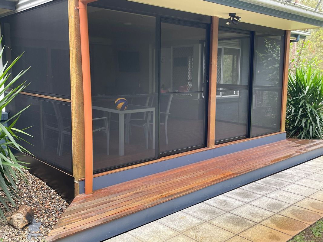 Screened porch with dark screens, wooden frame, and outdoor seating.