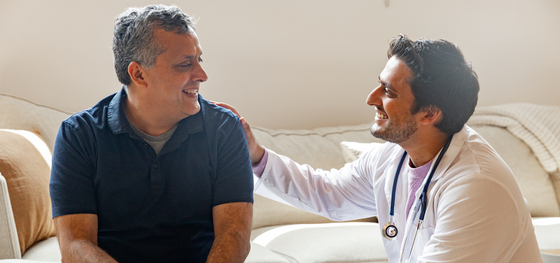 A male doctor and a male patient both smiling.