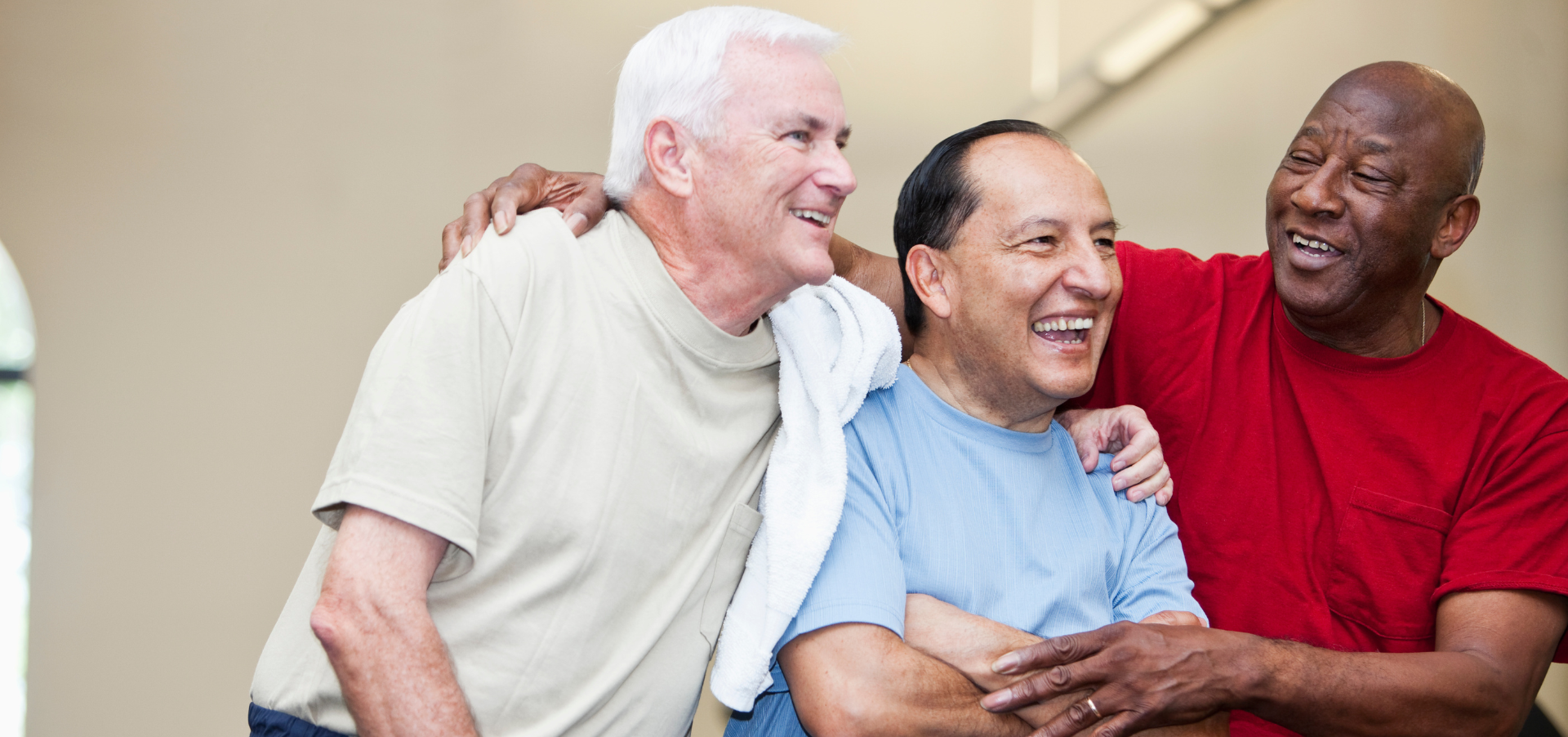Stock image of three men being friendly and smiling at a gym.