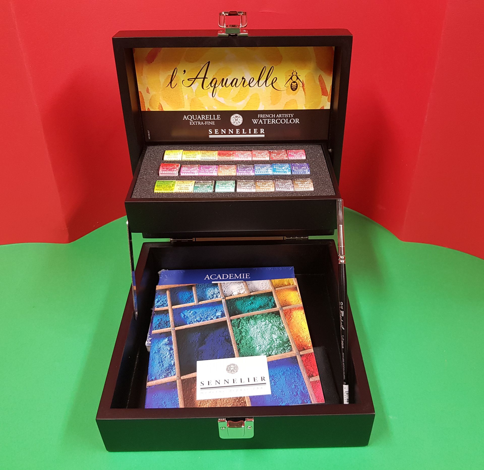 Set di acquerelli in scatola nera aperta, comprensivo di colori, pennello e libro d'arte.