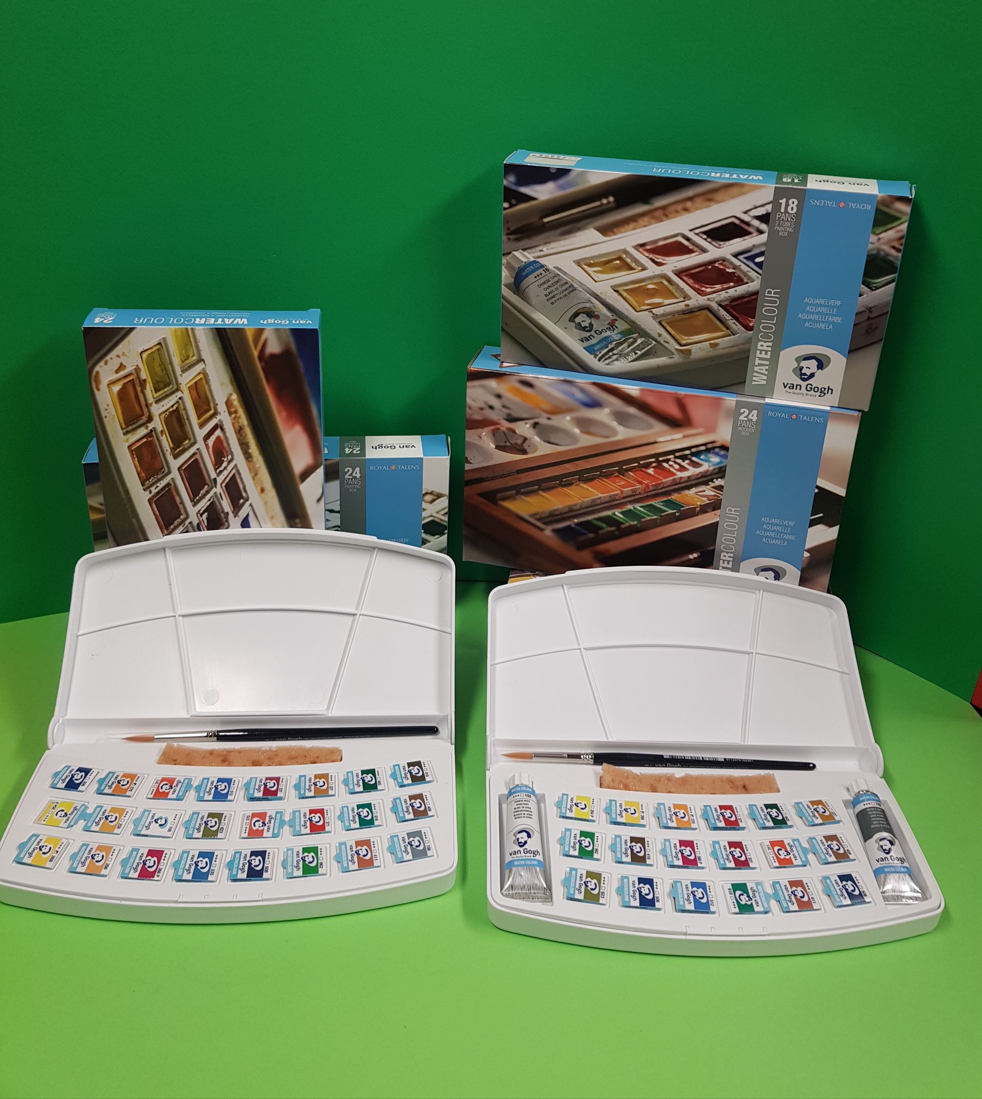 Due tavolozze bianche di acquerelli con colori e pennelli, sullo sfondo scatole di acquerelli.