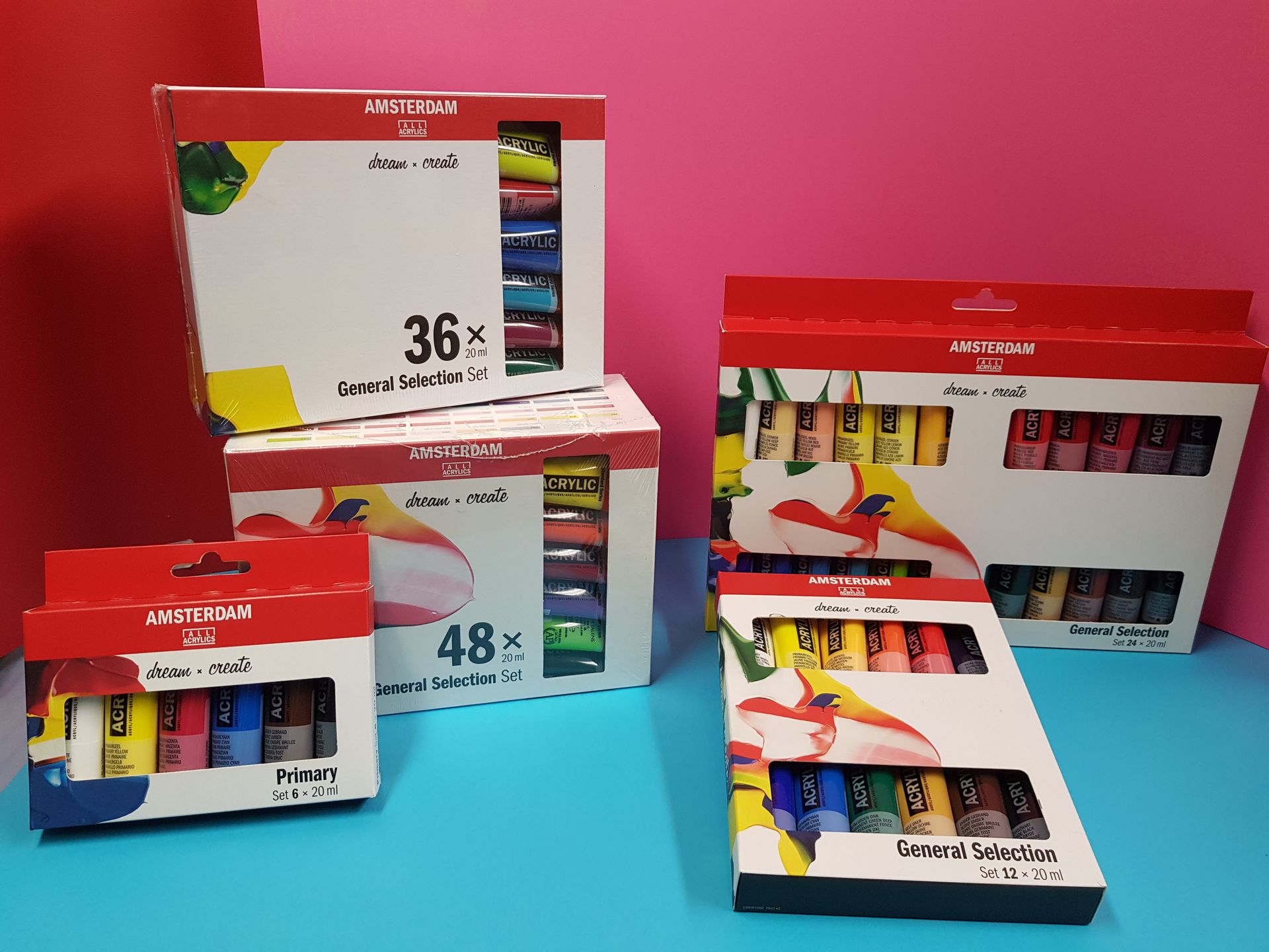 Set di tubetti di vernice in scatole di diverse dimensioni su sfondi blu, rossi e rosa.