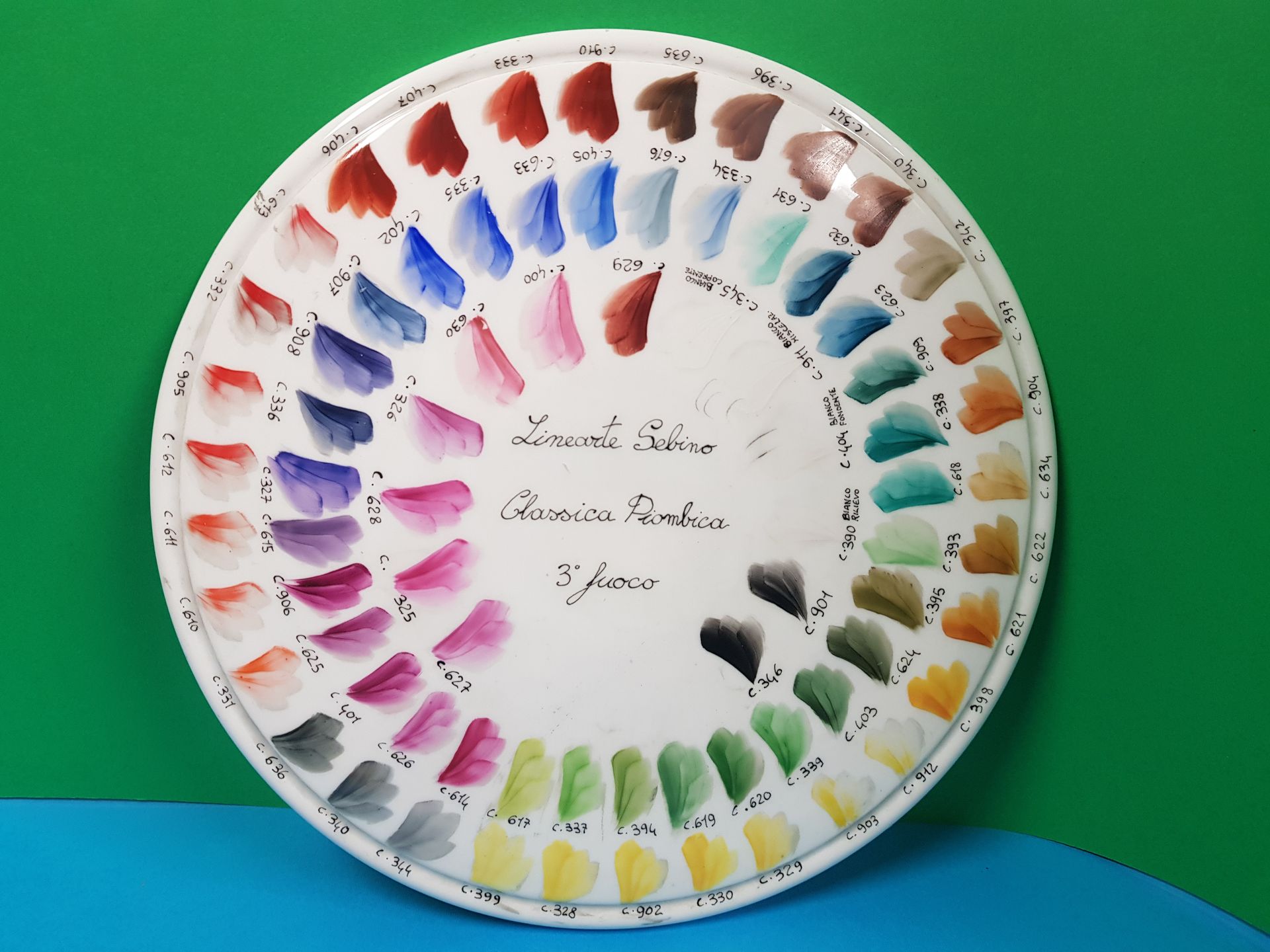 Mani che dipingono colorati motivi floreali su un piatto di ceramica, con tavolozze e pennelli a portata di mano.