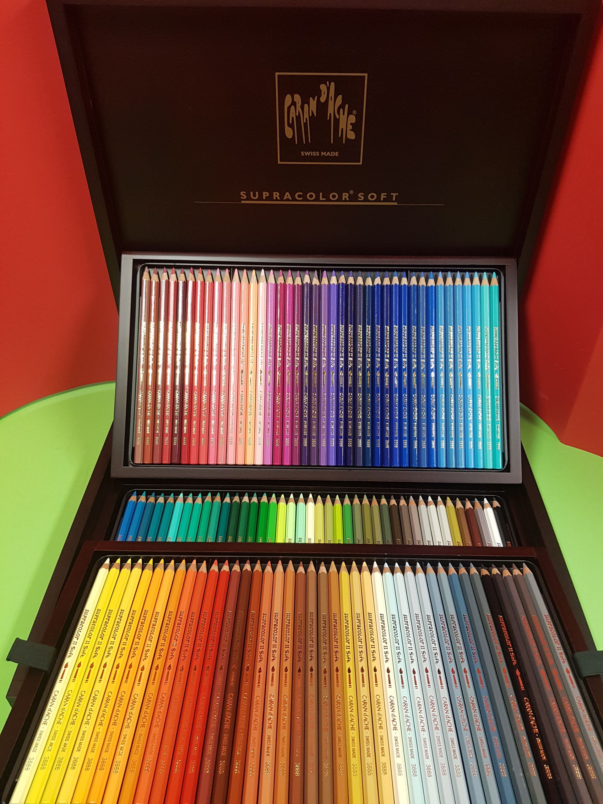 Valigetta in legno contenente una vasta gamma di matite colorate, in varie tonalità, disposte in file.