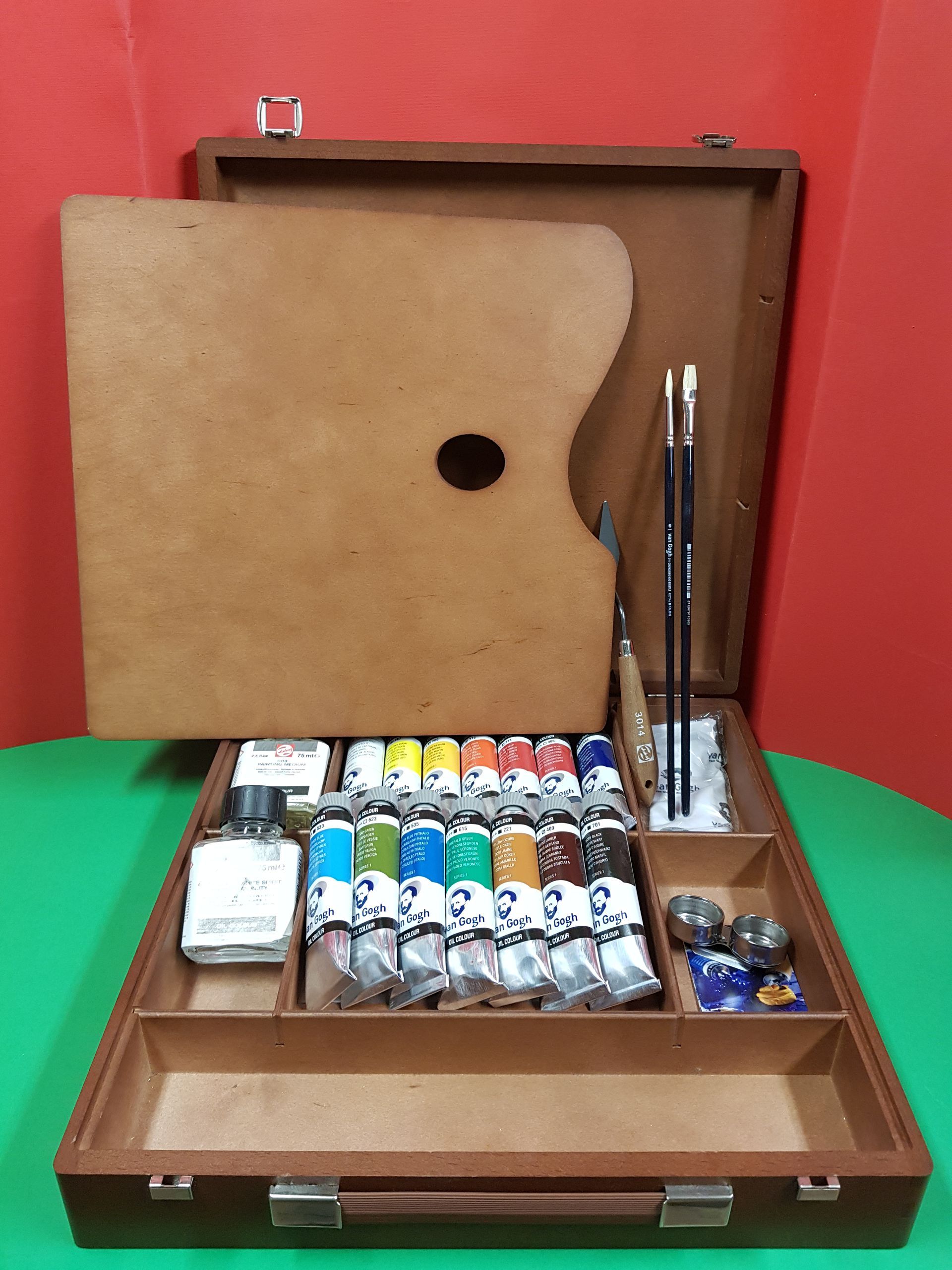 Kit d'artista in legno aperto, che rivela tubetti di vernice, pennelli, tavolozza e barattoli.