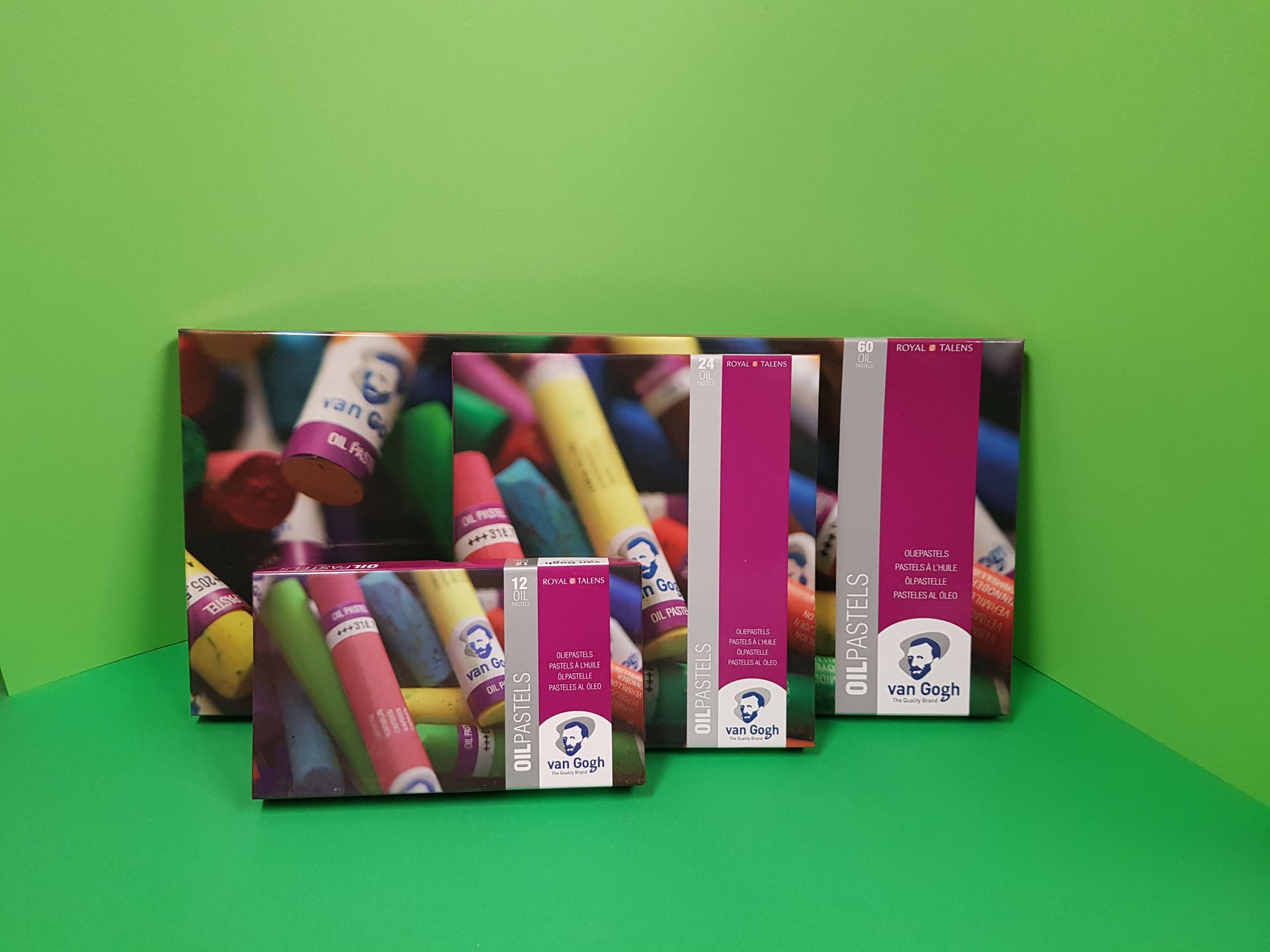 Scatole di pastelli artistici su sfondo verde. Le scatole variano in dimensioni e presentano decorazioni a pastello.