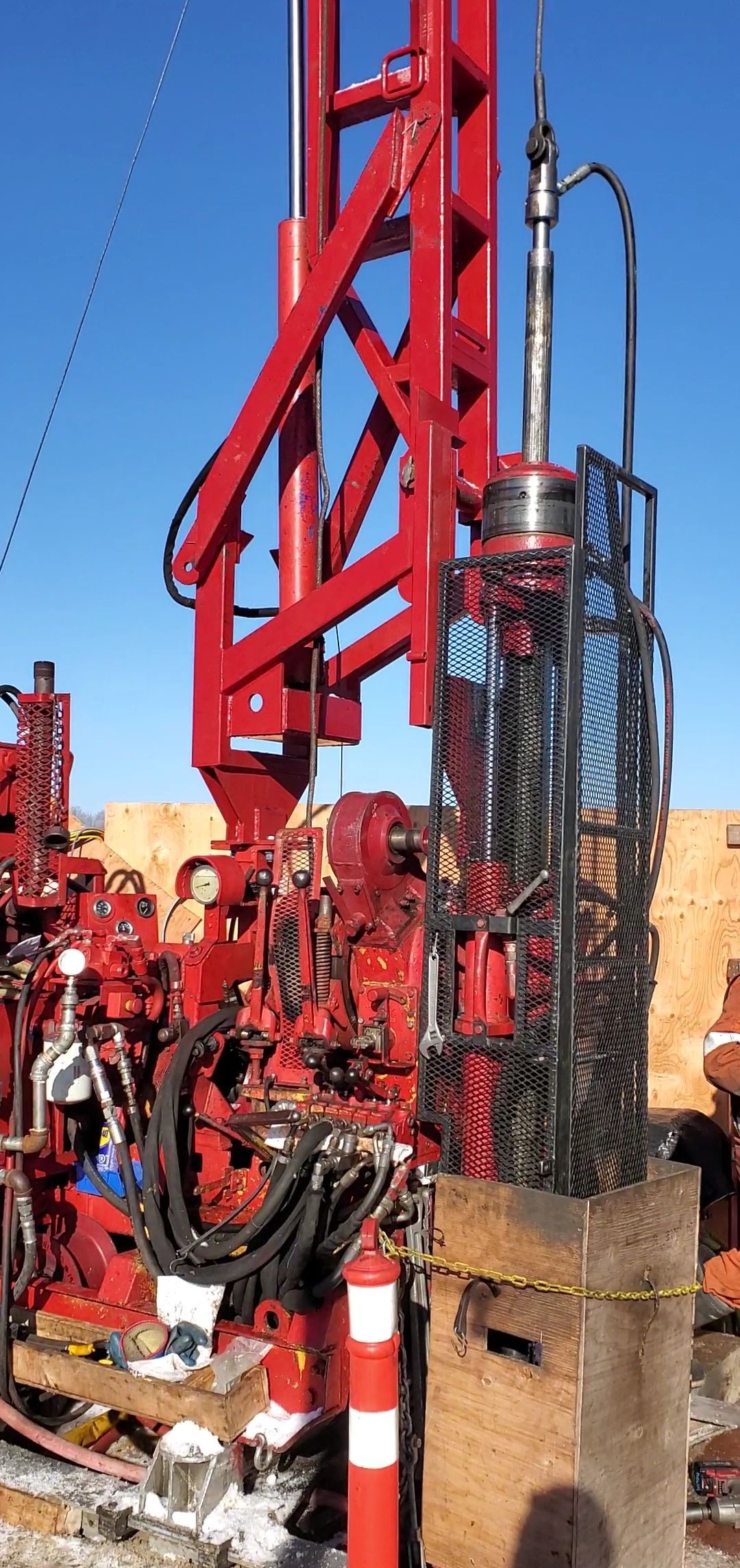 Engin de forage rouge en fonctionnement en extérieur, probablement sur un chantier de construction.