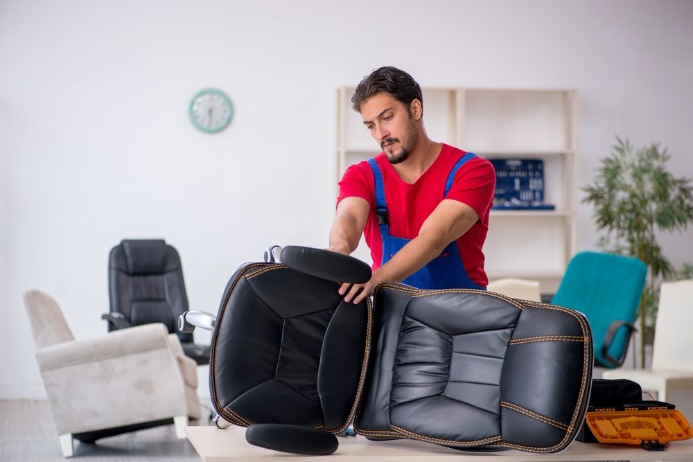 A Man Is Repairing An Office Chair In An Office — Allwood Upholstery In Manunda, QLD