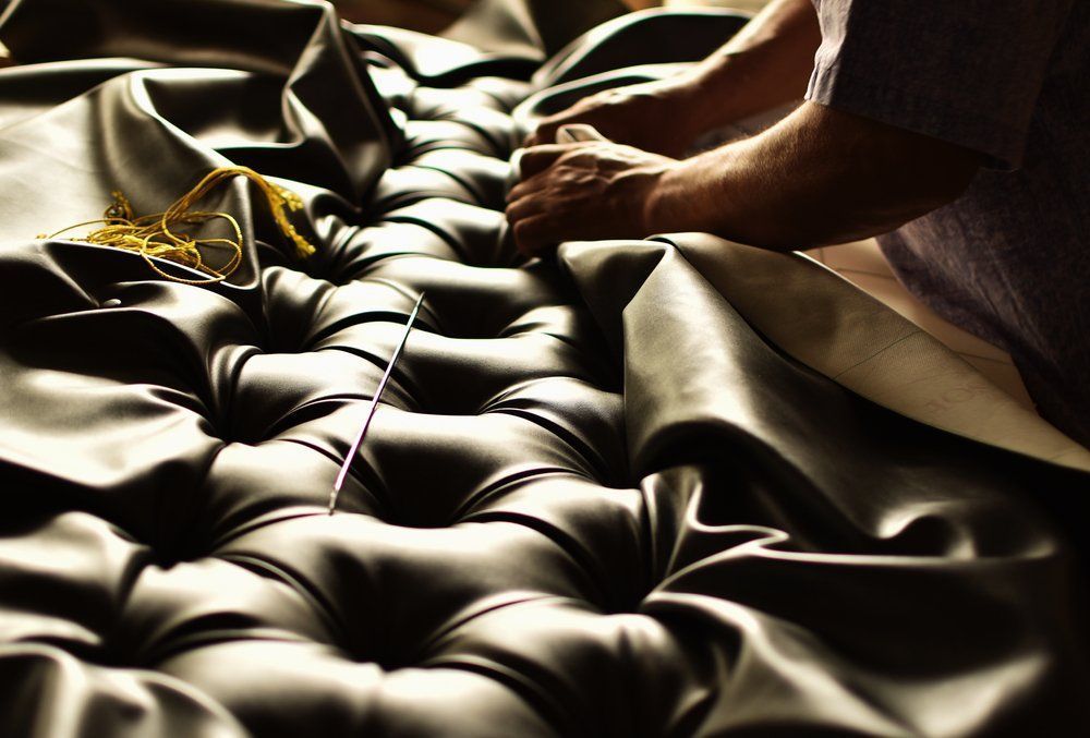 A Person Is Working On A Tufted Leather Couch — Allwood Upholstery In Manunda, QLD