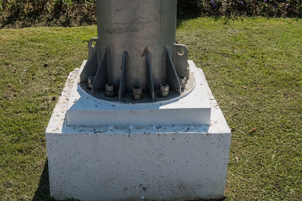A metal pole is sitting on top of a concrete base.