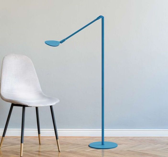 Un lampadaire bleu est posé à côté d'une chaise blanche
