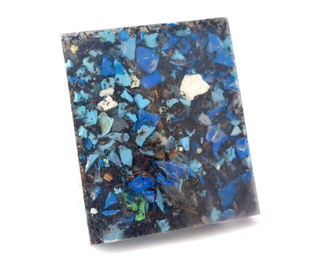Mosaico abstracto azul y negro con fragmentos blancos y verdes dispersos.