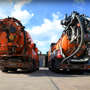 Zwei orangefarbene Lastwagen stehen am Straßenrand