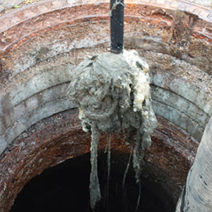 In einem Brunnen hängt ein großer Erdhaufen an einer Stange.