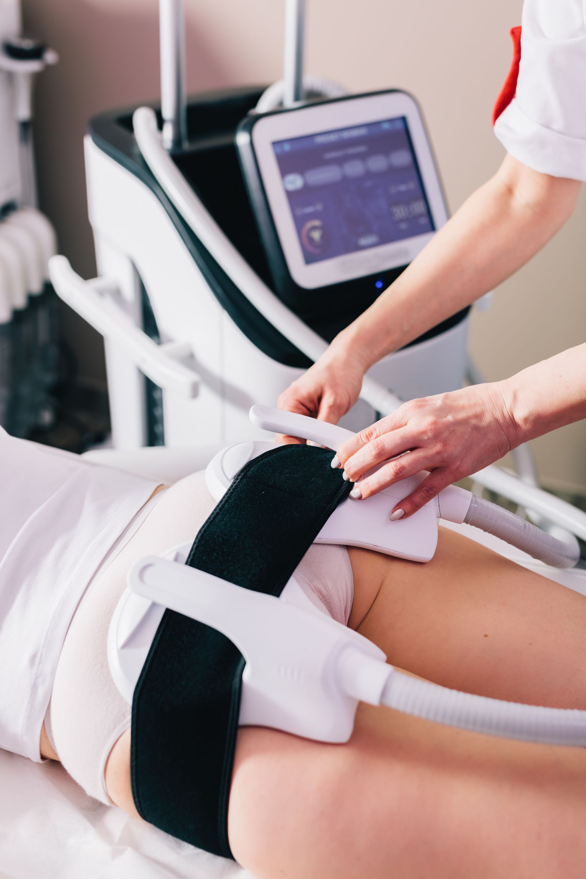 A woman is laying on a bed getting a massage from a machine.