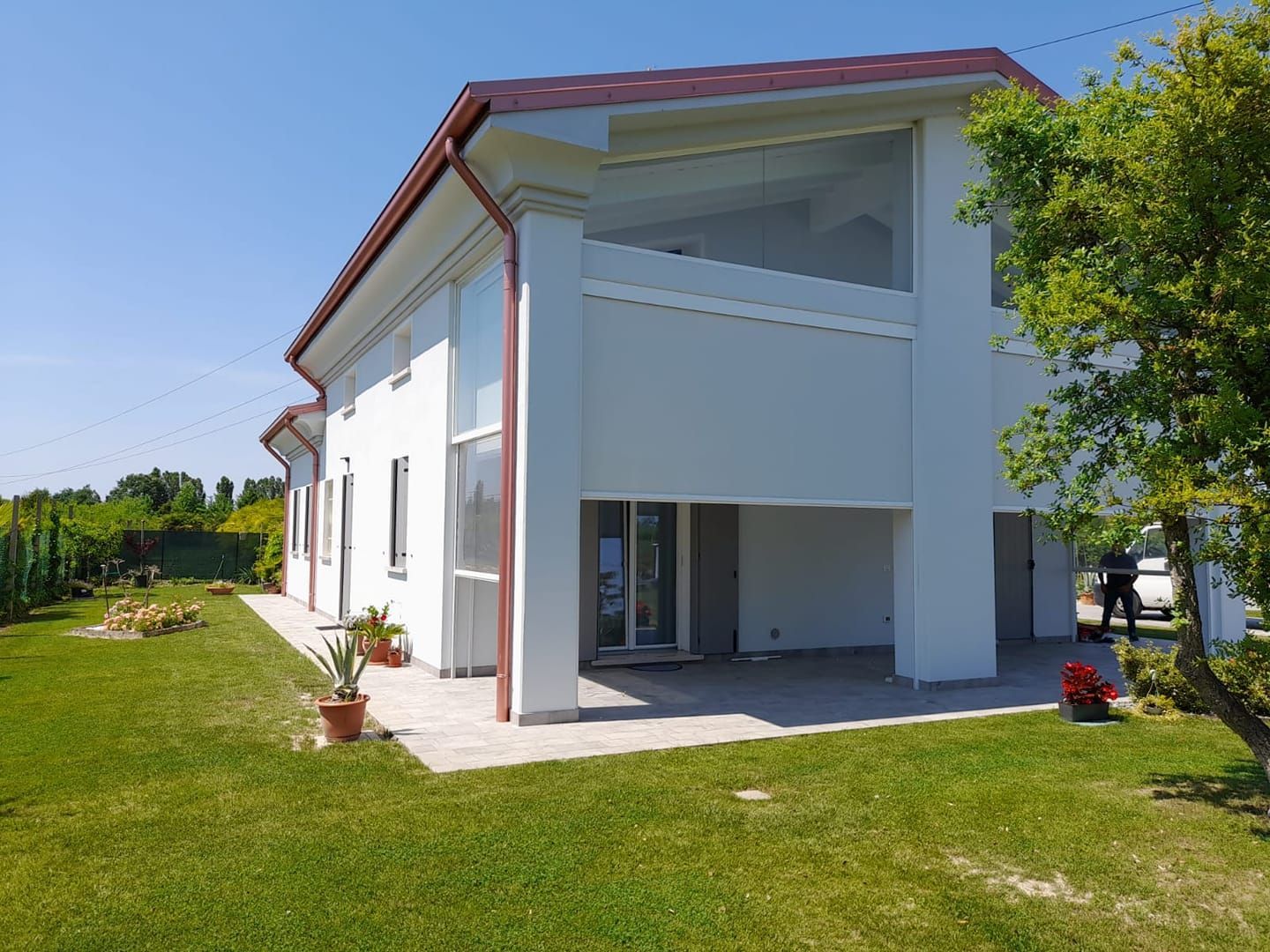 Una casa bianca con il tetto rosso e un grande prato davanti.