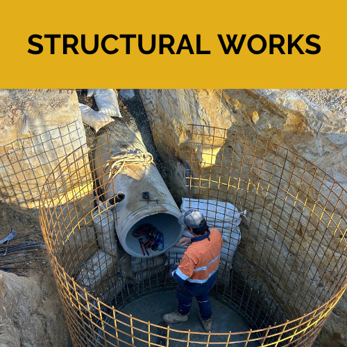 A man standing in an excavated hole reinforced with steel ready for concrete to be poured around it.