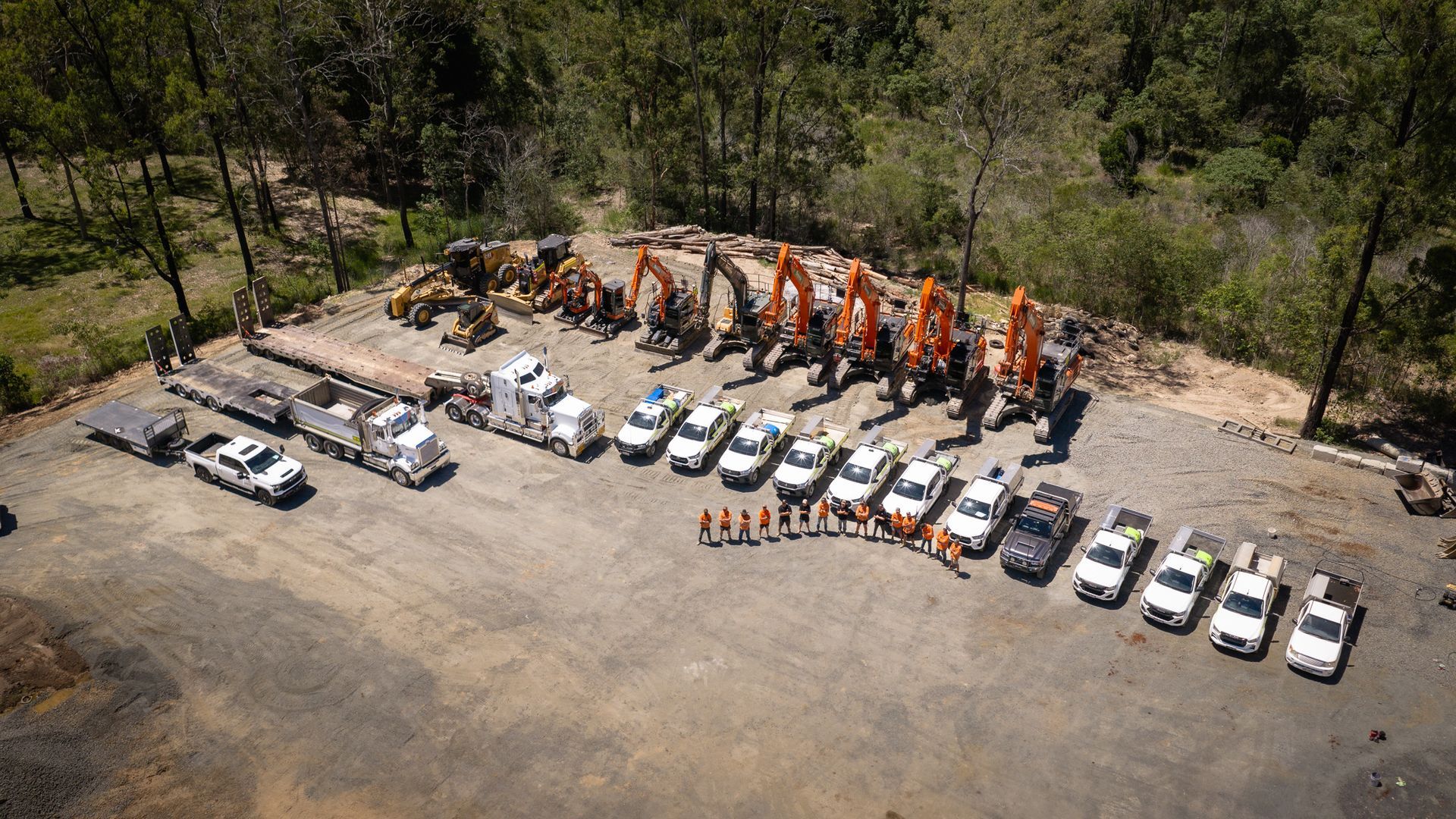 A white Spencer civil & earthworks ute is parked in a dirt lot next to one of their excavators.