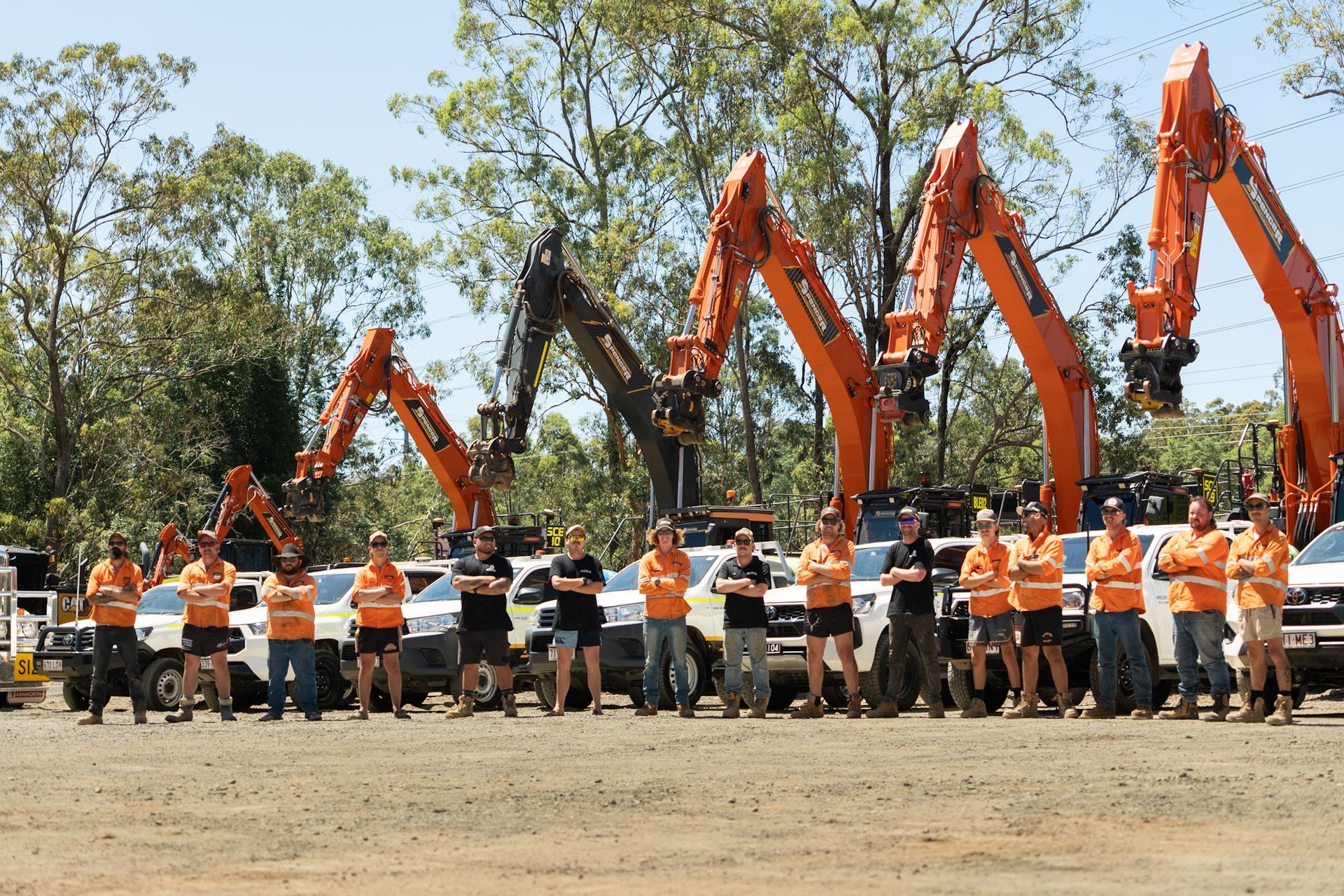 A white spencer civil & earthworks ute is parked on a cleared dirt pad next to a spencer civil & earthworks excavator.