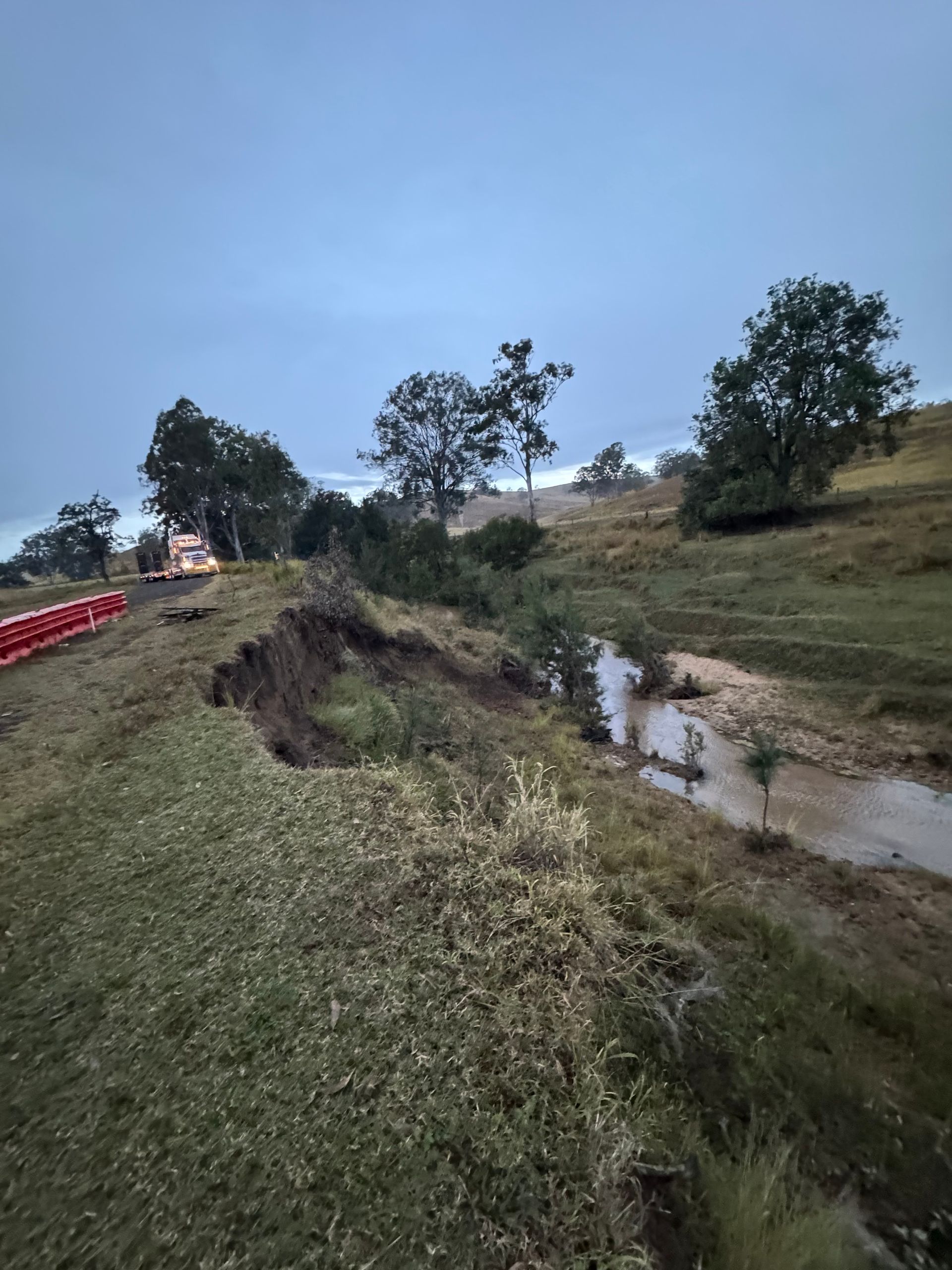 A damaged hillside that eroded down into a river bed, soon to be repaired by spencer civil & earthworks.