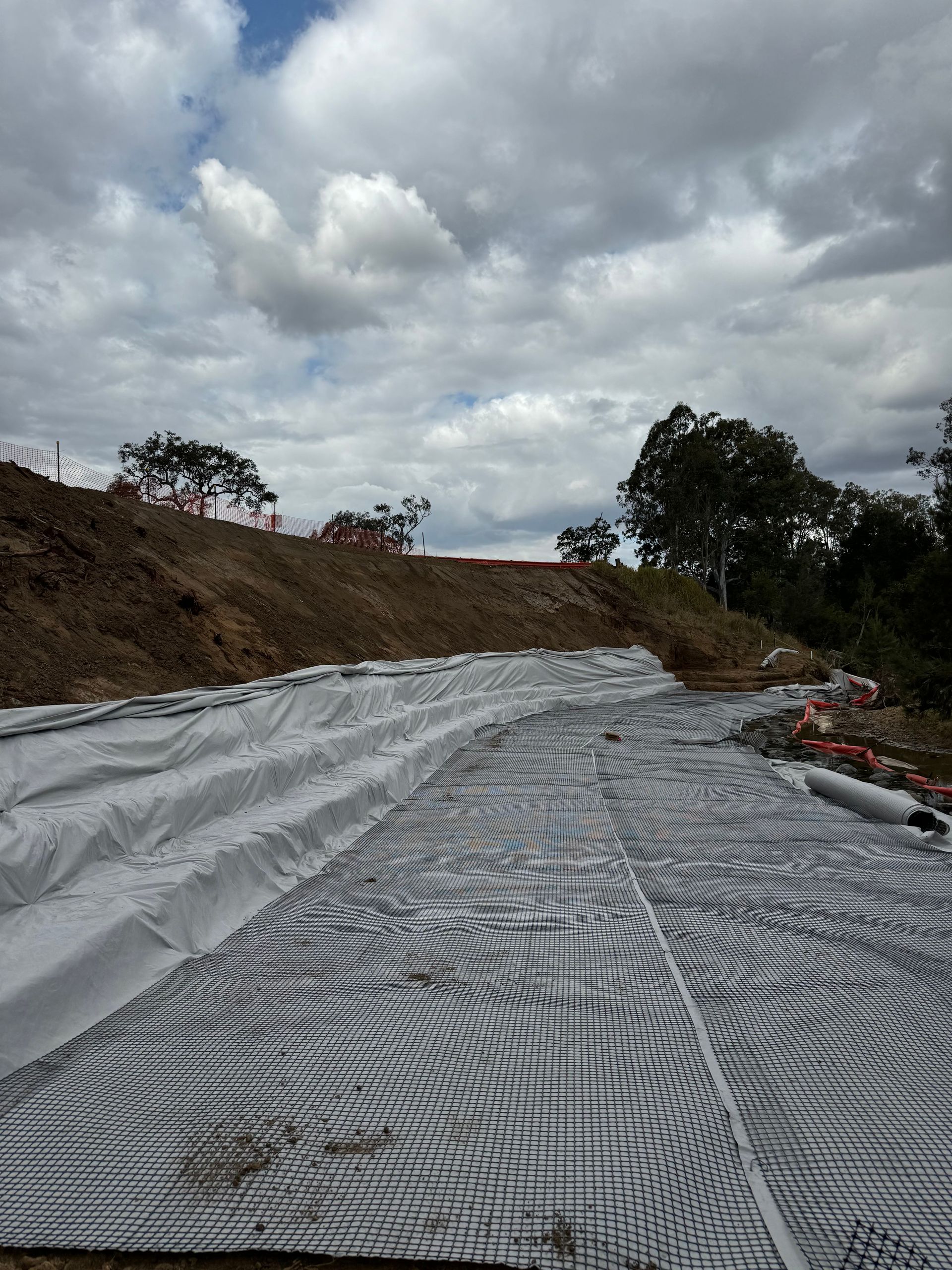 Geotextile matting has been installed along the surface and edge of a river bank. 