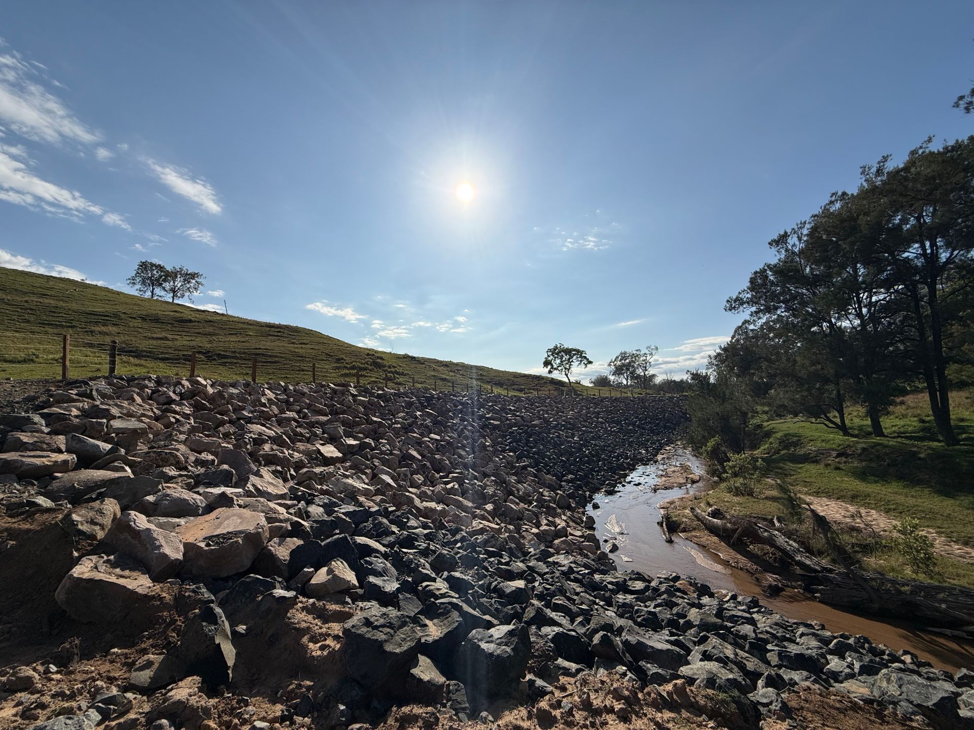 A photo taken after repairs have been made to an eroded hillside. There is now a rock revetment to assist in drainage.
