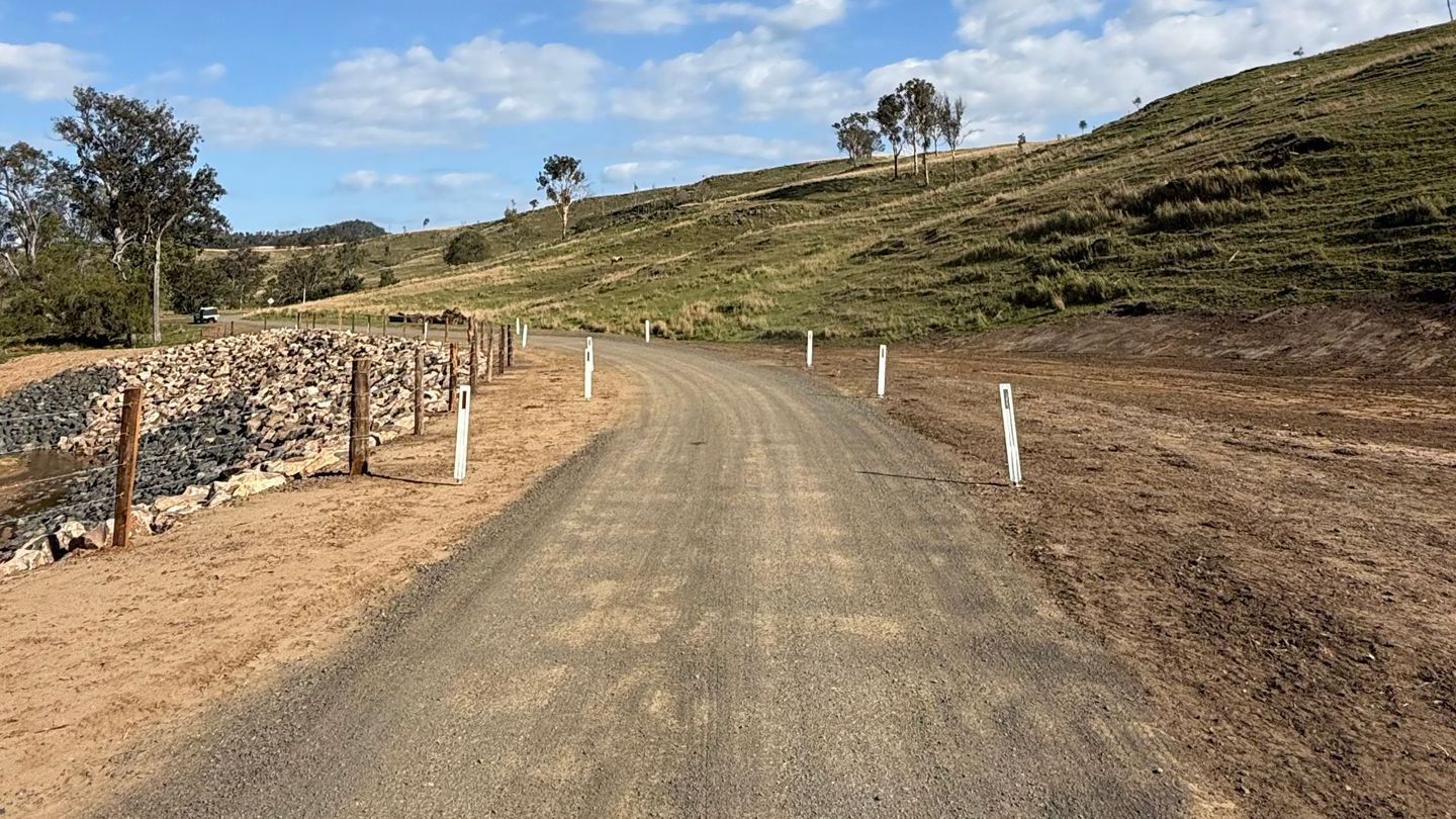 A dirt road with a fence on the side above the recently completed erosion waterway repair,