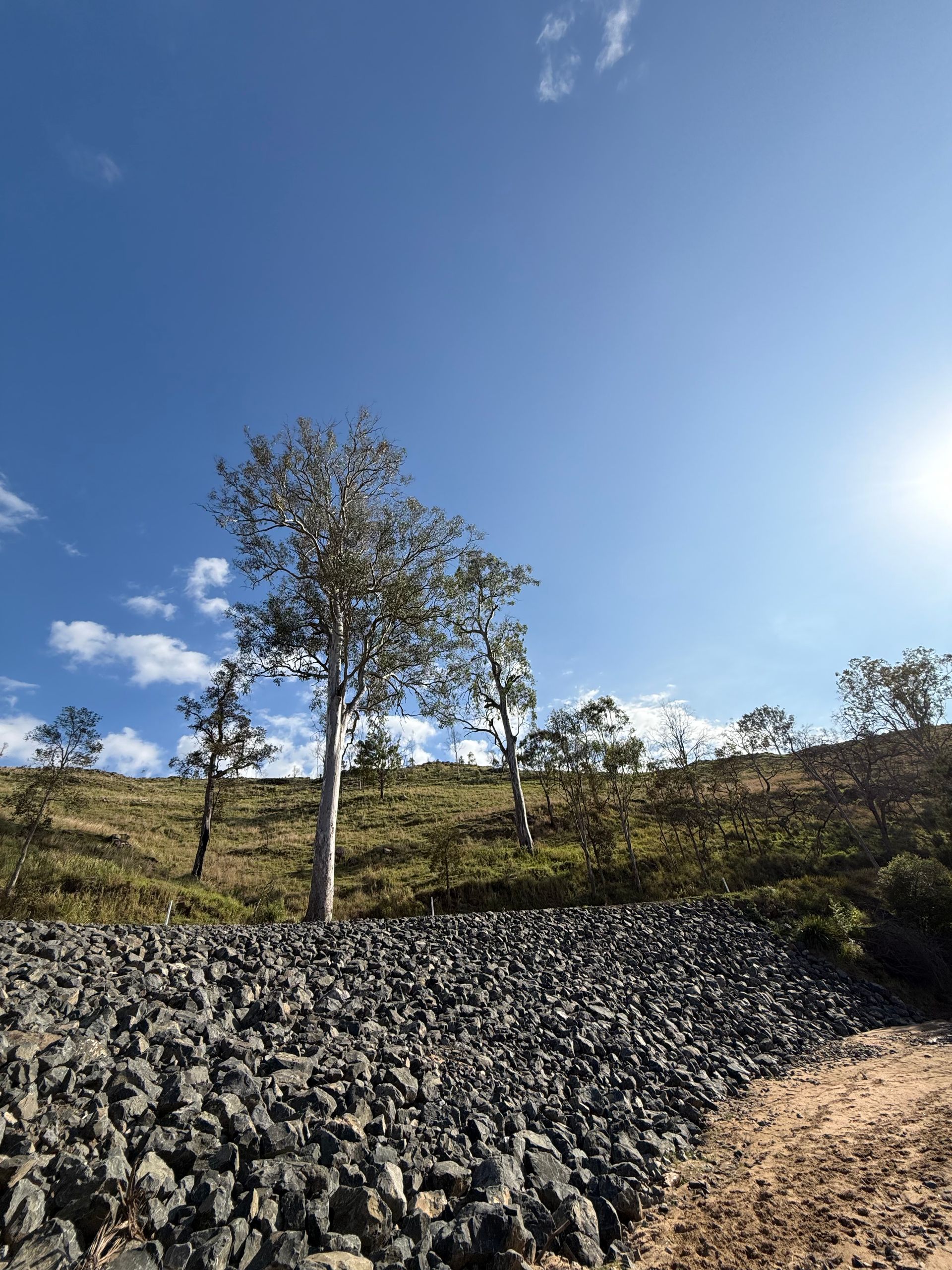 A photo taken after repairs have been made to an eroded hillside. There is now a rock revetment to assist in drainage.