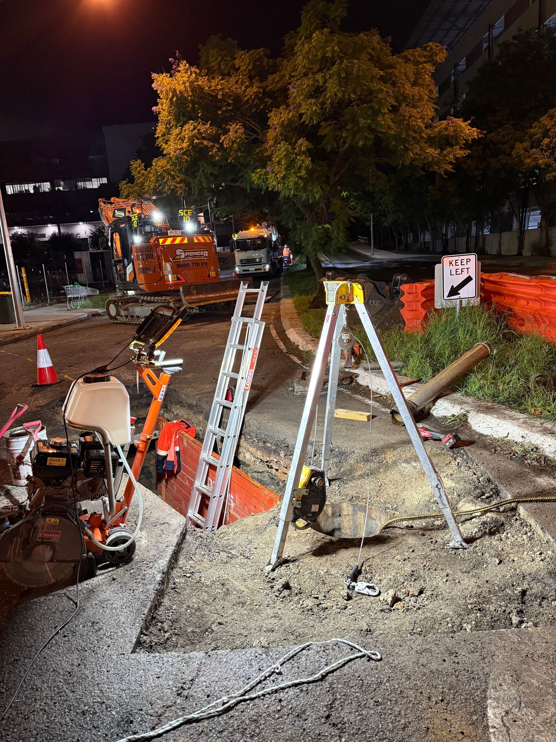 Ongoing progress on a project on butterfield street. there is an open hole in the ground with ladders and equipment.