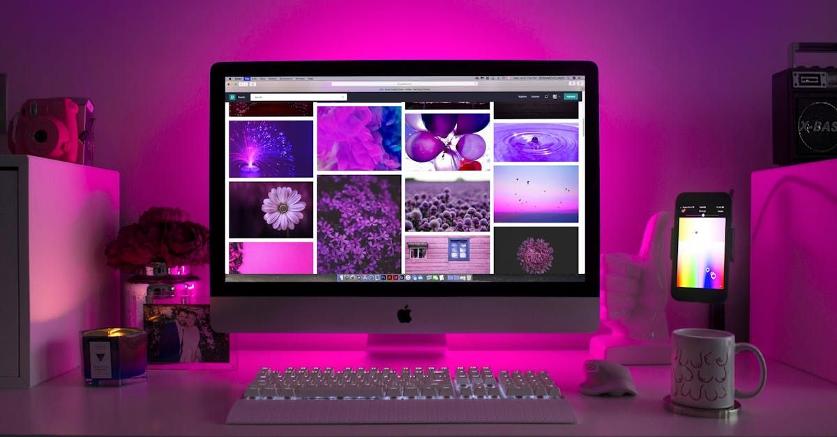 A computer monitor is sitting on a desk with purple lights behind it.