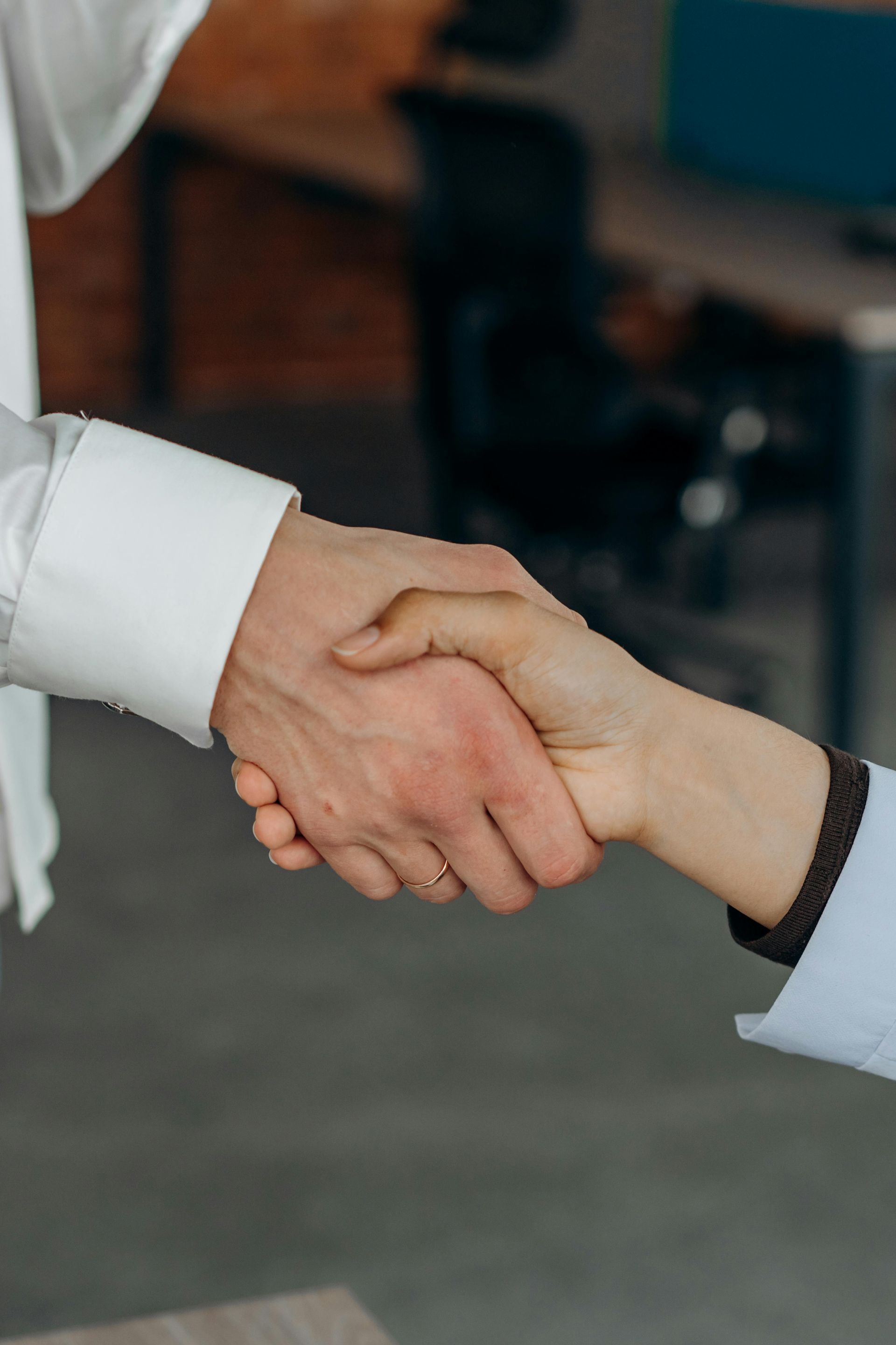 A man and a woman are shaking hands in an office.