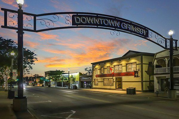 A downtown grimesy sign over a street with a sunset in the background.