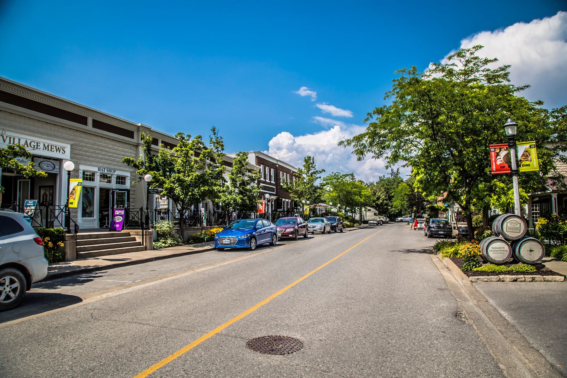 A row of cars are parked on the side of a street in a small town.