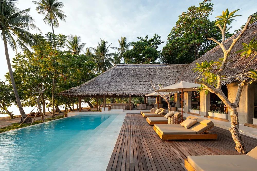 White and brown frogfish with speckled skin, blending with a rocky ocean floor.
