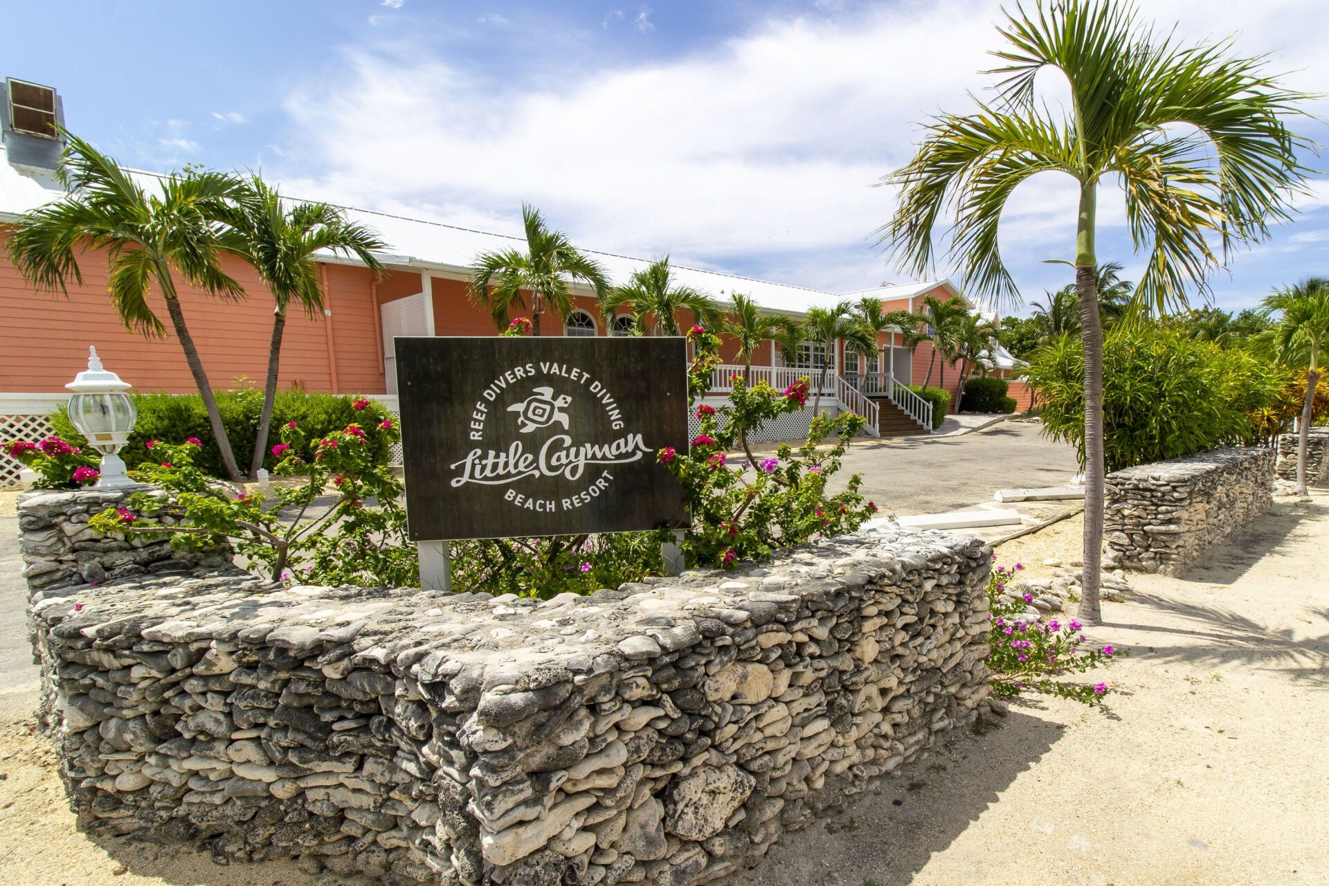 Sign for Stella Maris Resort Club in the Bahamas, coral-colored buildings, palm trees, sunny day.