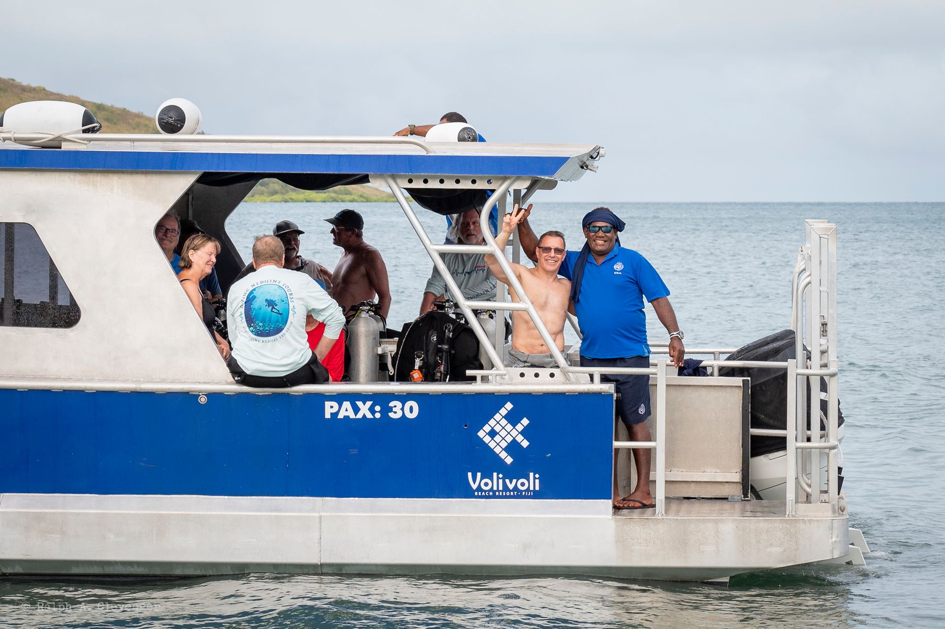 People on a blue and white boat in the water, some waving.