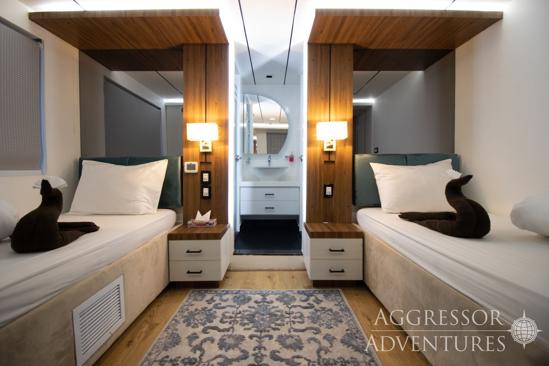 Twin beds in a cabin with wood accents, bedside tables, and a view to a bathroom.