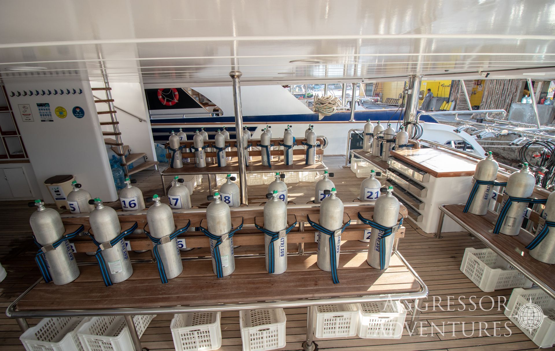 Scuba diving tanks lined up on a boat deck, ready for use.