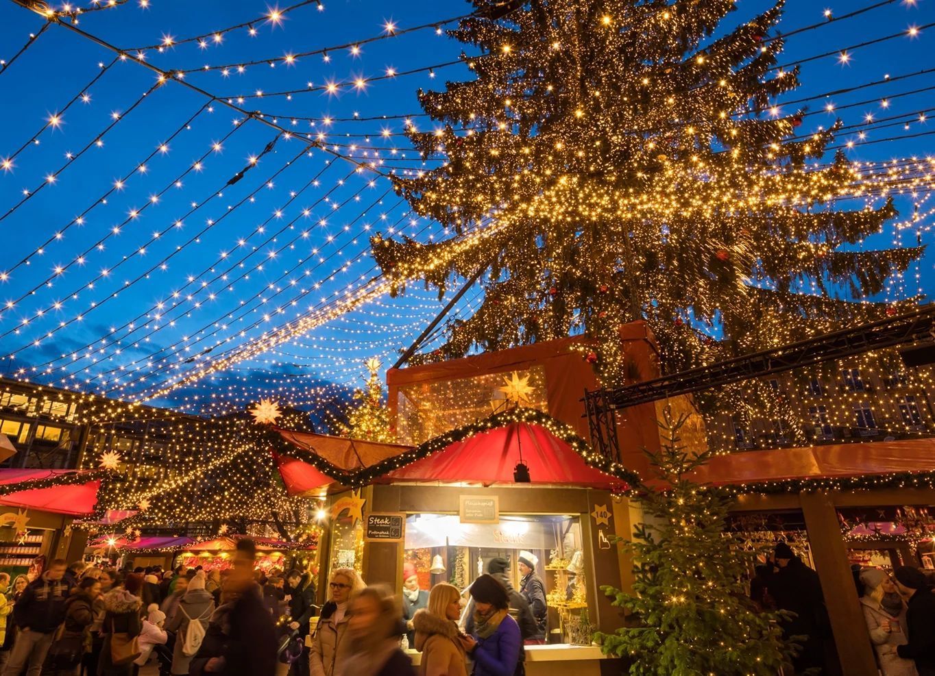 Beachfront huts on wooden dock, palm trees, blue water, sunny day.